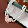 Elegant double-strand white pearl necklace featuring a detailed pink butterfly pendant. - Double Layer Butterfly Artificial Pearl Necklace / White-Pink