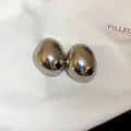 Primer plano de pendientes de botón ovalados irregulares minimalistas con acabado metálico pulido - Estilo Ovalado Irregular / Plateado
