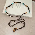 Close-up detail of ethnic style woven beaded waist chain accessory on a book prop - 48# Waist Chain - Dark Coffee