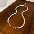 Elegant pearl necklace with gold geometric metal accents on a rustic wooden tray - Triangle Square Patchwork