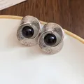 Close-up of silver-tone twisted wrinkled earrings with a central black bead - Silver-Black