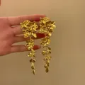 Detailed view of elegant gold-tone wrinkled metal flower tassel earrings held by hand. - Wrinkled Petal Tassel Style / Gold