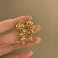 Detailed view of fashionable gold-tone crumpled metal petal tassel drop earrings with silver needle. - Wrinkled Metal Tassel Style / Bright Gold