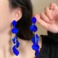 Detailed view of elegant royal blue petal tassel earrings worn by a model on a black top - Blue Petal Tassel Style / Blue