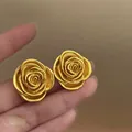 Detailed macro view of elegant gold rose flower earrings with textured layered petals - Rose Stud Style / Gold