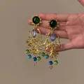 Macro view of ornate vintage gold drop earrings featuring vibrant green and blue gemstones - Baroque Bead Tassel Style / Gold-Green-Blue