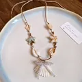 Elegant summer shell necklace with pearls and starfish charms on a ceramic plate. - Natural Conch Shell Style