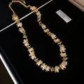 Detailed close-up view of a gold-plated necklace with irregular square frames and zircons - Necklace / Gold