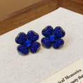 Close-up view of elegant vintage-style four-petal flower stud earrings with blue rhinestones - Gun Black Jewelry / Dark Blue