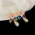Close-up of pink ceramic flower earrings with teardrop pearls and iridescent bows - Hook Style / Pink