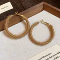 Close-up of brown fabric woven hoop earrings with a cozy fuzzy yarn texture for winter - Light Coffee