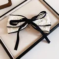 Close-up of white textured fabric bow hair clip with black ribbon accent details - No.3 Spring Clip - White Large