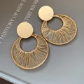 Makroaufnahme von runden, goldfarbenen, hohlen, drahtumwickelten Ohrhängern auf grau - Silberstift Runder Hohl-Anhänger-Stil / Gold