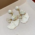 Detailed close-up shot of handmade cream raffia ginkgo leaf earrings with white flower - Silver Post Gingko Leaf / White