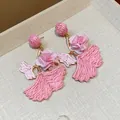 Close-up of pink raffia woven ginkgo leaf earrings with fabric flower accents. - Silver Post Gingko Leaf / Pink