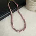 Macro view of vintage pink pearl necklace detailing round glossy pearls and gold clasp. - 8mm / Champagne