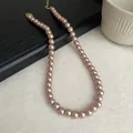 Close-up view of an elegant champagne pearl necklace with a golden clasp adornment - 10mm / Champagne