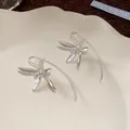 Macro di eleganti orecchini a gancio con fiori di iris in argento su un piatto di ceramica - Stile a Gancio / Argento
