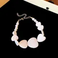 Detailed view of an irregular white heart necklace on a soft black velvet surface. - Bracelet / Silver-White