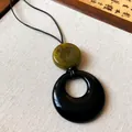 Close-up detail of a New Chinese style resin pendant necklace with a black ring and green bead - Olive Green Marble Bead / Black-Green-Leather Rope-Oval
