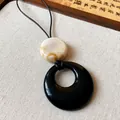Detailed close-up of a minimalist resin ring necklace with black and marbled beige discs - Beige Marble Disc / Black-Beige-Leather Rope-Oval