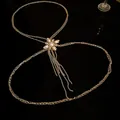 Elegant gold body chain with pearl flower and rhinestone tassels on black background - Gold Body Chain / Gold