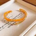 Elegante brazalete abierto de doble capa ondulada de acrílico naranja y oro - Naranja