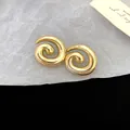 Detailed close-up of golden spiral stud earrings with smooth finish and retro style - Spiral Style / Gold