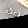 Detailed macro view of silver-toned spiral geometric acrylic stud earrings with smooth finish - Spiral Style / Silver