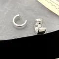 Close-up of minimalist silver chunky C-shaped hoop earrings with a glossy finish - C-Shape Spiral Style / Silver