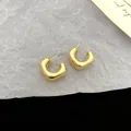 Detailed macro view of elegant gold geometric C-shaped stud earrings with a smooth finish - C-Shape Spiral Style / Gold