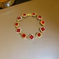 Close-up of sparkling red clover and round crystal bracelet in gold finish - Bracelet-Red