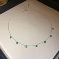 Vue détaillée d'un collier ras du cou en argent avec sept pendentifs en zircon vert ronds. - Vert
