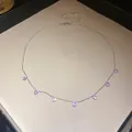 Vue détaillée d'un collier de couleur argentée avec sept pendentifs en zircone violette. - Rose