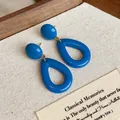 Gros plan de boucles d'oreilles pendantes en acrylique bleu rétro sur présentoir tissu - Style Goutte de Balle (HE29977) / Bleu