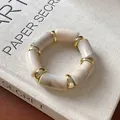Close-up of marbled cylindrical beads and golden spacers on a vintage elastic bracelet - Cylindrical Smudge Style (HB3370) / Gold-Off-white