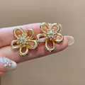 Close-up detail of elegant gold flower stud earrings featuring sparkling zirconia clusters - Gold