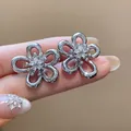 Close-up of silver-tone zircon flower stud earrings featuring elegant hollow petals - Silver