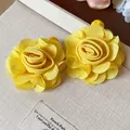 Close-up detail of elegant yellow chiffon flower earrings on a textured beige display - Flower Stud Earrings / Yellow