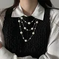 Detailed close-up of a layered pearl necklace worn over a black vest and white shirt. - French Luxury Triple Style (25#) / Gold-White Pearl