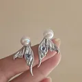 Close-up detail of silver mermaid tail stud earrings with heart blue zircon and white pearl - Silver Fishtail Sterling Silver Post Earrings