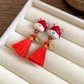 Primo piano di orecchini mascotte rossi con monete d'oro e nappe in un portagioie beige. - Stile Nappina Leone in Stile Cinese (45#)