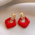 Primo piano di eleganti orecchini geometrici rossi con dettagli in metallo martellato oro - Stile Geometrico Rosso Martellato (32#)