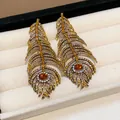 Detailed view of ornate gold-tone feather earrings encrusted with yellow rhinestones - Gold Base Brown Yellow