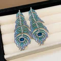 Detailed macro shot of feather-shaped stud earrings with blue and teal crystals - Silver Base Blue Green