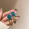 Close-up of statement earrings with matte blue top and crumpled gold-tone metal - Geometric Irregular Dangle (HE7973) / Gold (Blue Pendant)