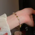 Close-up detail of a gold-plated bangle featuring vibrant square-cut zircons on wrist - Style 34 / Gold