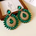 Detailed view of green teardrop emerald earrings with sparkling rhinestone floral design. - 21-Stone Style / Green