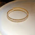 Primo piano di un bracciale aperto a tre strati con perle bianche e strass scintillanti - Oro