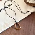 Detail view of a retro brown irregular geometric pendant on a minimalist black cord - Brown